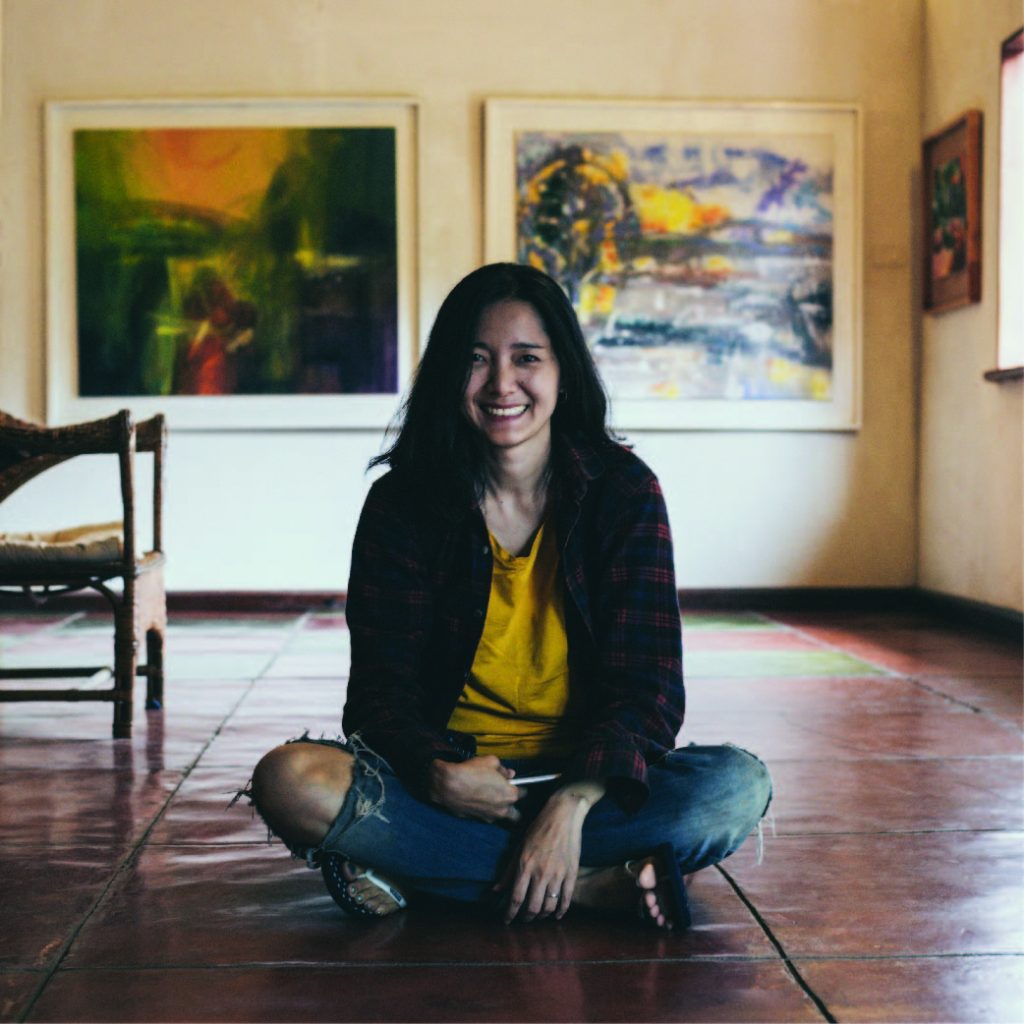 Girl sitting on the floor of her studio in front of her art.